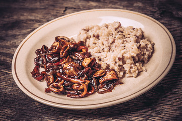 Delicious calamari rings with rice in plate on rustic wooden table