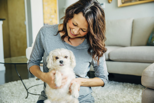Caucasian woman petting dog in living room