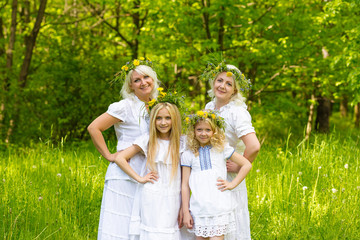Fototapeta premium Happy family resting on the nature in the summer. Mom and daughter with wreath in the flowers in the park