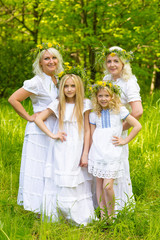 Fototapeta premium Happy family resting on the nature in the summer. Mom and daughter with wreath in the flowers in the park