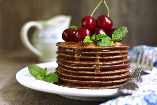 Chocolate pancakes with honey and cherry.