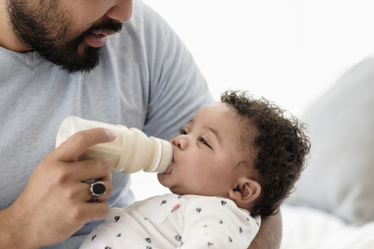Father bottle feeding baby son