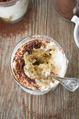 Partly eaten classic italian dessert Tiramisu served in  glass. Selective focus.