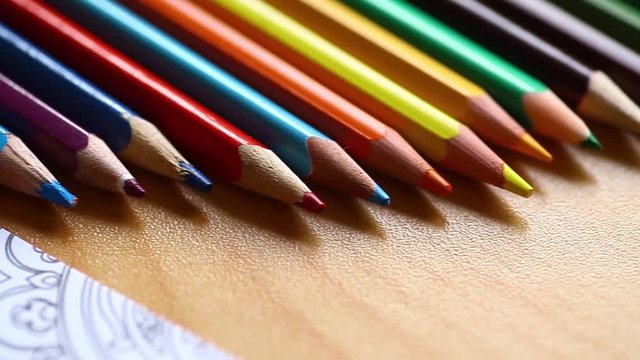 Sliding video of some pencils and a hand coloring an adult coloring book.