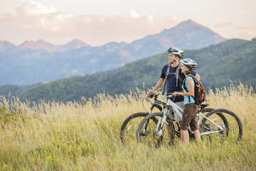 Caucasian couple riding mountain bikes in field