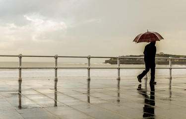 Hombre con paraguas paseando al amanecer por la ciudad