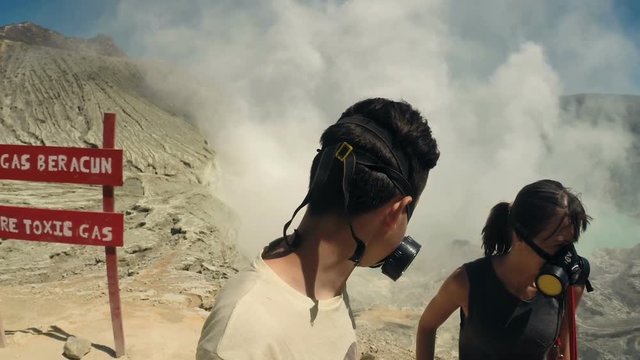 Teenager in gas mask taking selfie photo, video by Ijen volcano in Java, Indonesia
