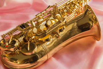 Obraz na płótnie Canvas beautiful golden saxophone on delicate Pink silk background