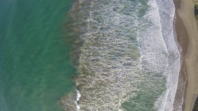 Aerial view of waves breaking on sandy beach 