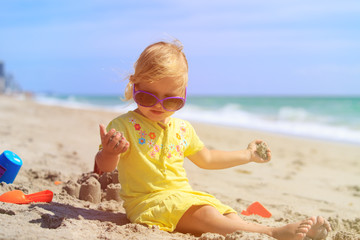 cute little girl play with sand on beach