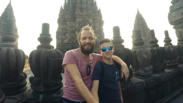 Father with son taking selfie photo by Prambanan temple
