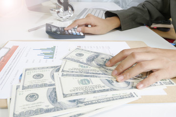 Fototapeta premium business woman hold money dollar with calculator on tablet as fi