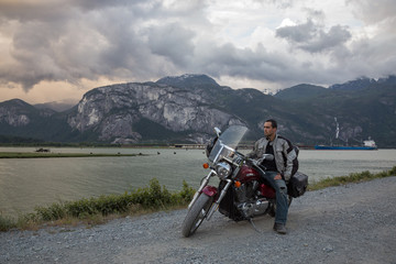 Motorcycle Rider on a dirt road by the river, with mountainous background. Taken in Squamish, BC, Canada.