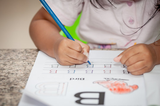 Child hand drawing her homework with crayon