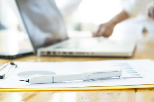 Businessman analyze data from business report chart. Top view of wooden working desktop with labtop.vintage tone Retro filter effect,soft focus,low light.(selective focus).