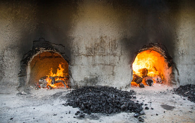 fire burning in a traditional oven underneath halwa cooking pans in Nizwa, Oman