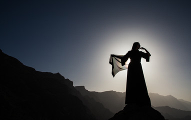 a woman in traditional Emirati dress (abaya) in mountains of Oman