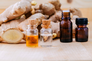 Bottles of ginger oil and ginger on wooden background with selec
