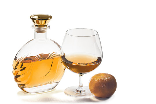 Bottle and snifter brandy with mandarin on white background
