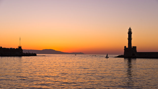 Panoramic view of the entrance to Chania harbor with lighthouse at sunset, Crete, Greece