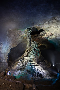 Lit lava column at the dark and empty Manjanggul Lava Tube Cave on Jeju Island in South Korea.