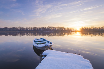 łódka na jeziorze zimą przy ośnieżonej przystani