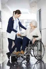 Physiotherapist Consoling Senior Patient In Wheelchair