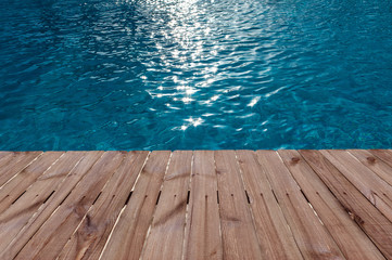 Old wooden floor and blue water in swimming pool
