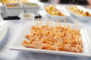 Small pieces of ham canapes lined up on white plate
