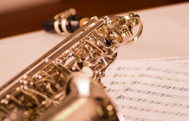 Obraz premium Closeup partly view of shiny saxophone lying on musical notes paper