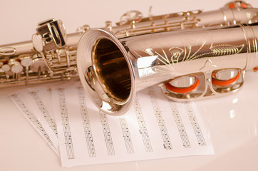 Obraz premium Closeup partly view of shiny saxophone lying on musical notes paper