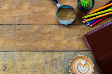 Office workspace with leather notebook, magnifying glass, coffee cup  and color pencil .Top view with copy space