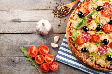 Delicious tasty pizza with ingredients on wooden table