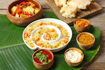 Fried rice with vegetables and flat bread on banana leaf over wooden background