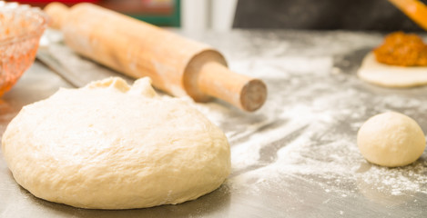 Closeup delicious bread dough shaped as ball before baking, rolling pin background