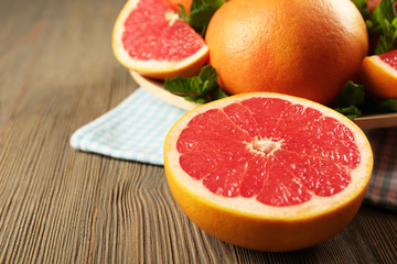 Fototapeta na wymiar Juicy pieces of grapefruit with fresh mint on wooden table, close up