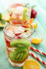Refreshing cocktails with ice, mint, pomegranate seeds and slices of fruits on blue wooden background