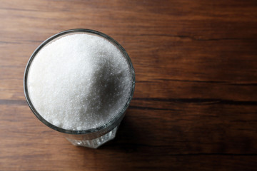 Highball glass with granulated sugar on wooden table