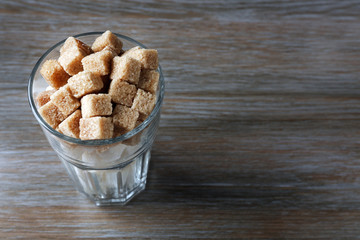 Highball glass with brown and white lump sugar on wooden table