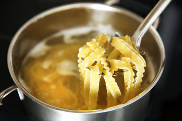Pasta in spoon over pan on stove in the kitchen