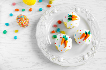 Plate with Easter cupcakes and eggs on wooden table