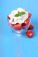Ripe strawberries with cream on a table