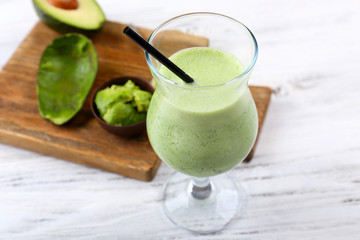 Delicious fresh avocado smoothie on white wooden background