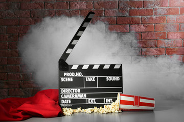 Clapper board and pop corn on wall background