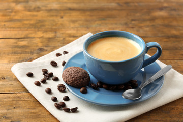 Cup of coffee with cookie on wooden table
