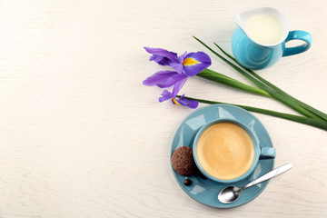 Cup of coffee with irises on wooden table