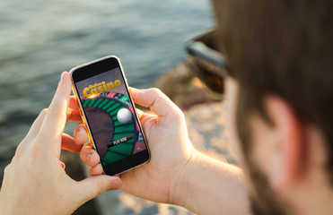 Man using his mobile phone on the coast playing online casino