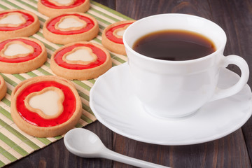 cookies with jelly and cup of coffee on bamboo napkin