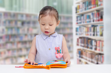 Little asian girl reading book in library