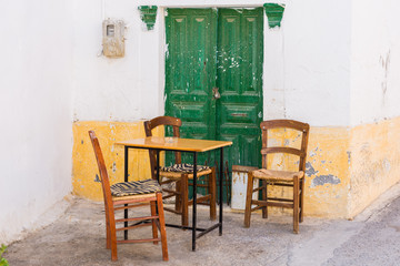 Fototapeta na wymiar Shady place with table and chairs in the village Pitsidia in the south of Crete. Pitsidia is situated in the south of the Ida mountain range close to Matala. A nice little village and destination